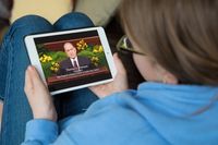 young woman looking at screen of President Monson