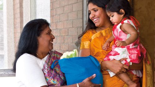 Relief Society president delivering a food order to a woman holding a young girl.