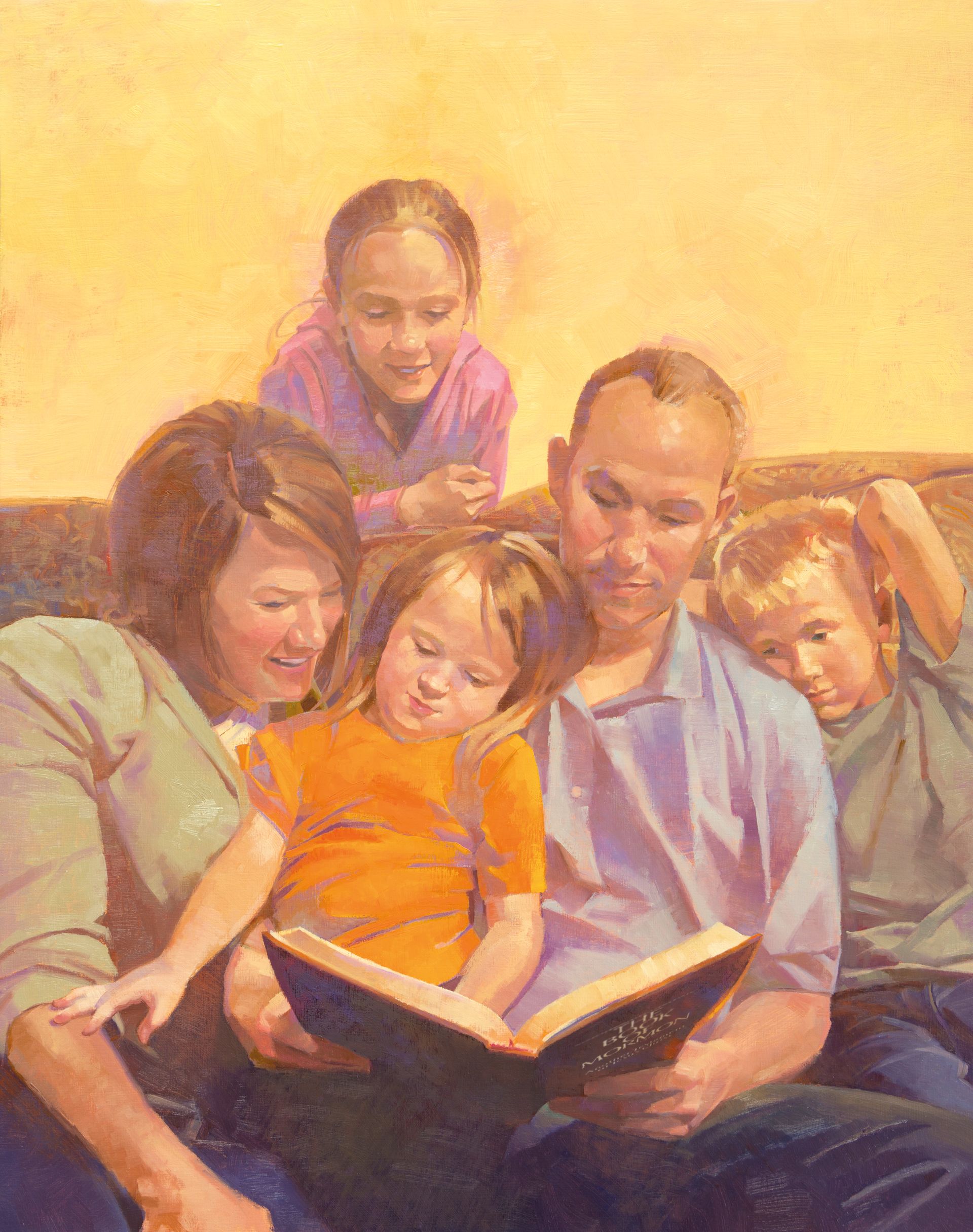 A family sits together on a couch and reads the Book of Mormon.