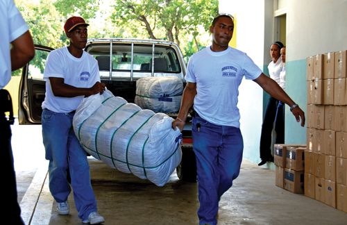 Two men unload a large package full of donated clothing from a pickup truck.