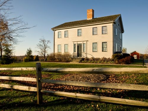 Clapboard home with a split-rail fence in the foreground