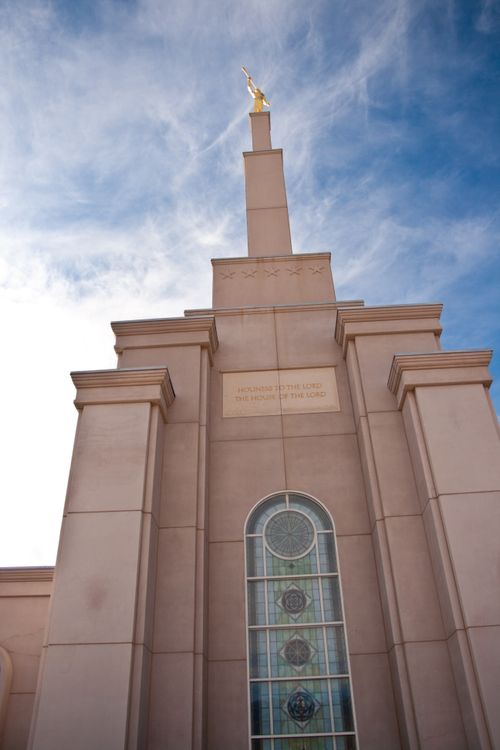 A view of the spire on the Albuquerque New Mexico Temple as seen from below, looking toward a blue sky with clouds.