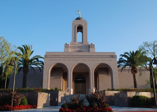 The front entrance of the Newport Beach California Temple in the late afternoon, with palm trees growing near the doors.