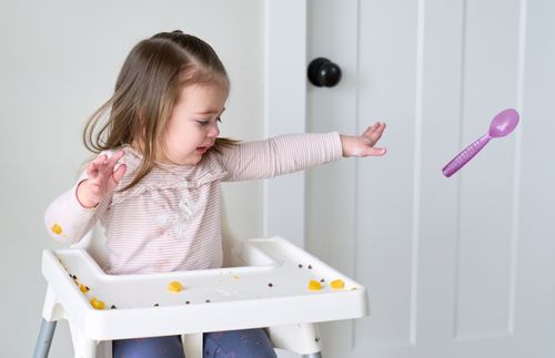 little girl tossing a spoon