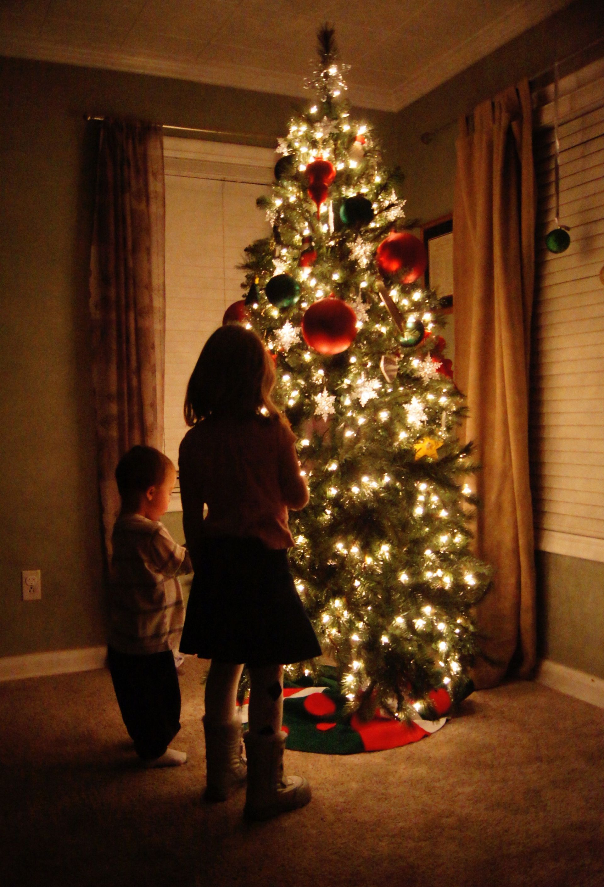 A tree lit up with children standing nearby.