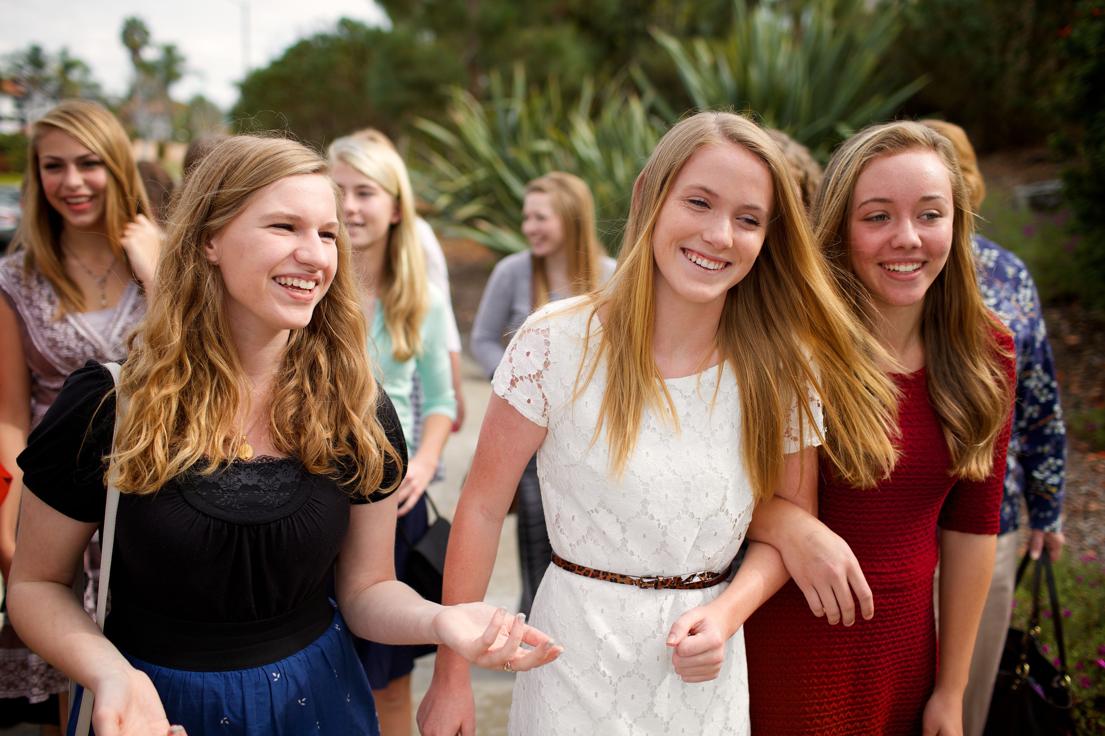 A group of young women in Sunday dress walk together outside.