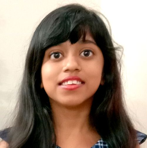 A photo of Emmelyn Pearl Sathyakumar standing in front of a Christmas tree