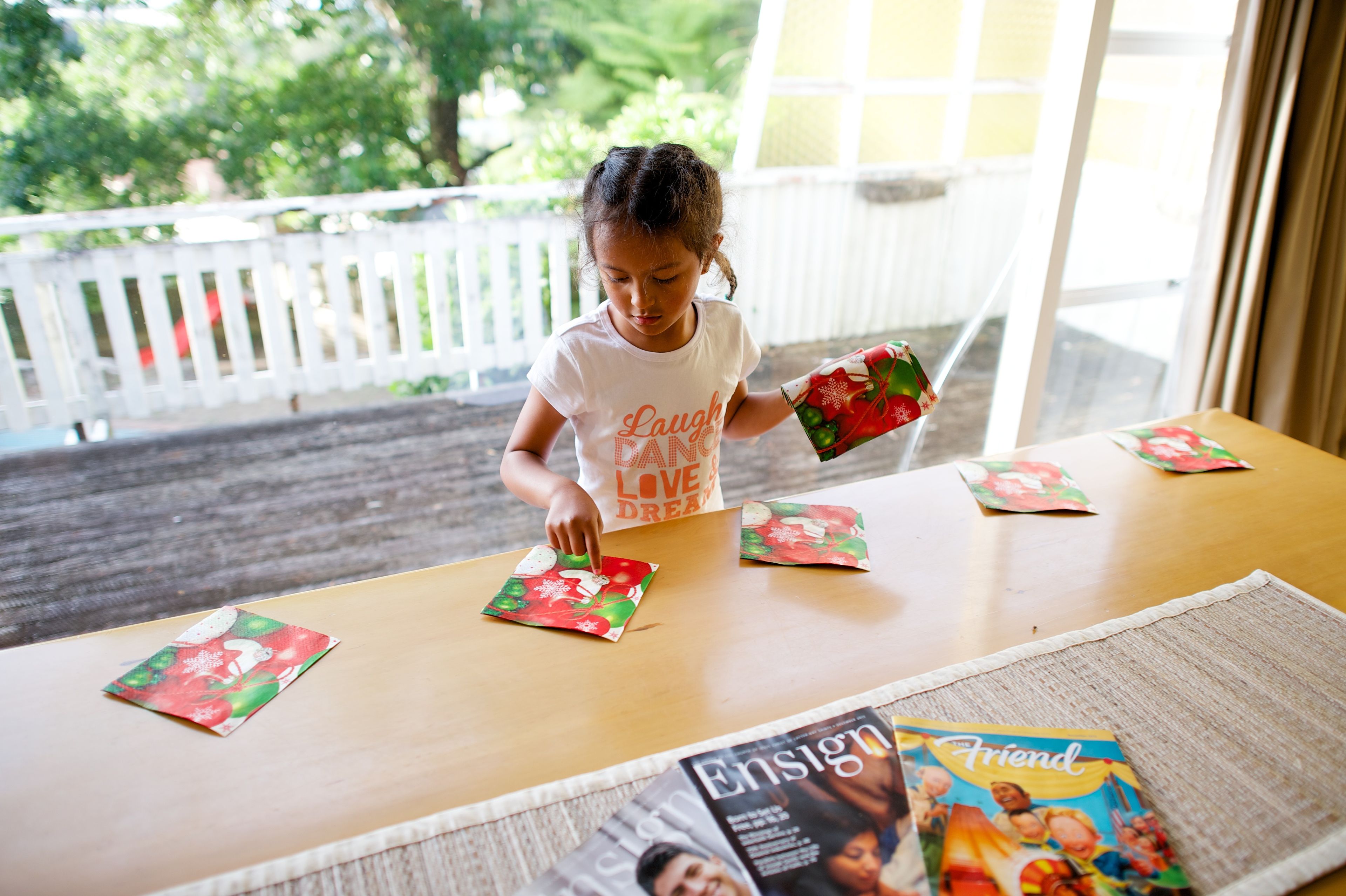 A young girl putting out Christmas napkins while setting the table.