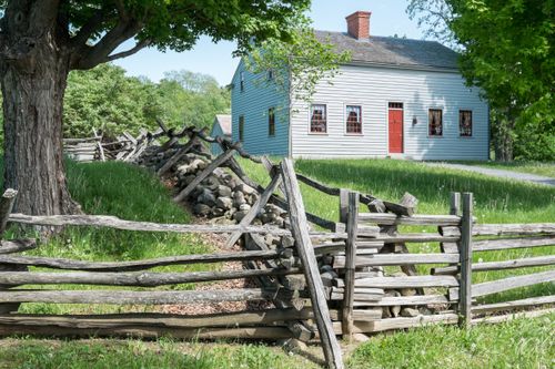 exterior view of white house with red door and a slatted wood fence in front