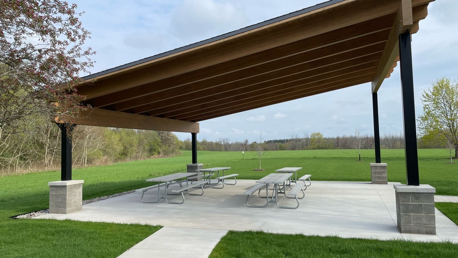 A covered picnic area on a concrete slab. 