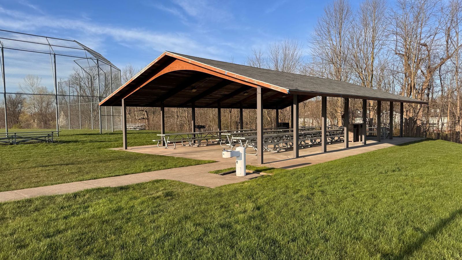 An outdoor pavilion with a grassy lawn in the background.