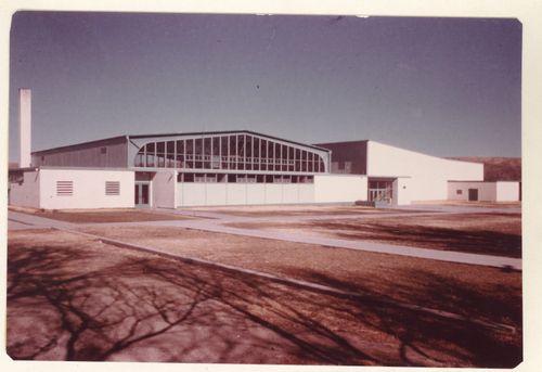 A building with a metal overhanging roof surrounded by grass and sidewalks.