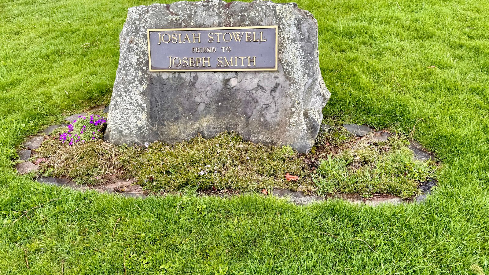 A large stone with a metal sign that reads Josiah Stowell friend to Joseph Smith.