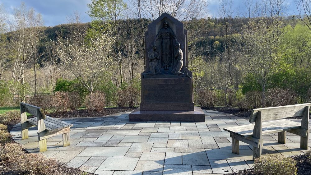 The Aaronic Priesthood Restoration Monument in the middle of a courtyard with two wooden benches. 