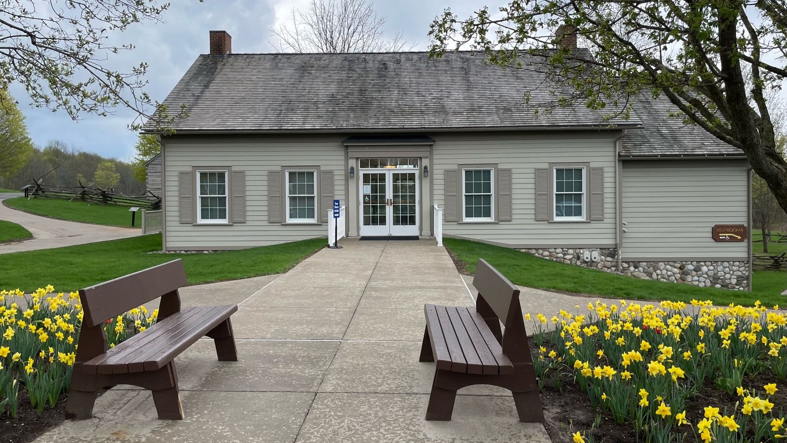 A concrete walkway leading to the Welcome Center door with benches and grass on either side.